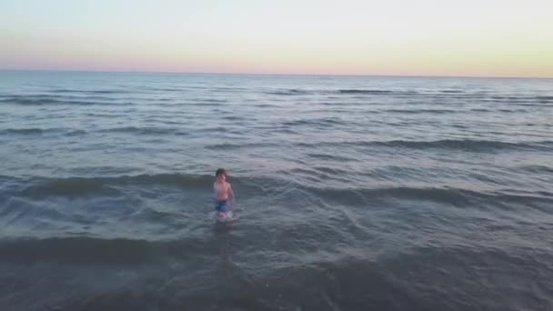Mały chłopiec bawi się w morzu. — Wideo stockowe
