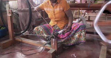 Hands of an old woman using an old spinning wheel to turn wool into yarn