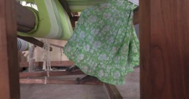 A footage of a woman using loom in a traditional asaian factory