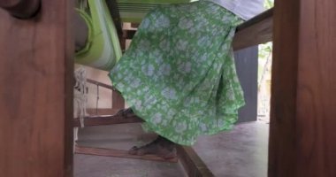 A footage of a woman using loom in a traditional asaian factory