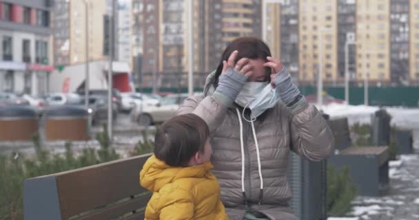 En mor sätter på sig skyddsmask på sig själv och sin lille son — Stockvideo