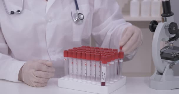 Covid-19 infekterade blodprov i vakuumrör i handen på forskare läkare i forskningslaboratorium — Stockvideo