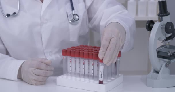 Covid-19 μολυσμένο δείγμα αίματος σε σωλήνα κενού στο χέρι του γιατρού επιστήμονα στο ερευνητικό εργαστήριο — Αρχείο Βίντεο