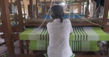 A footage of a woman using loom in a traditional asaian factory