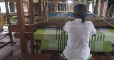 A footage of a woman using loom in a traditional asaian factory