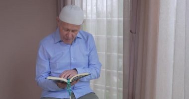 Evde Kuran okuyan yaşlı bir müslüman.
