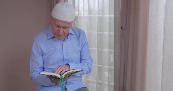 En gammal muslimsk man läser Koranen hemma — Stockvideo
