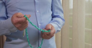 Tespih taşıyan yaşlı bir adamın dua eden elleri.