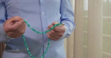 Tespih taşıyan yaşlı bir adamın dua eden elleri.