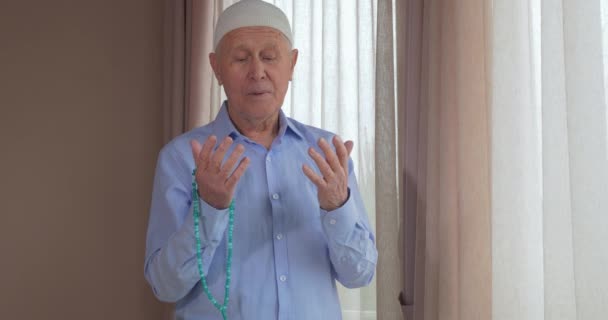 Ein alter Mann mit Rosenkranzperlen betet — Stockvideo