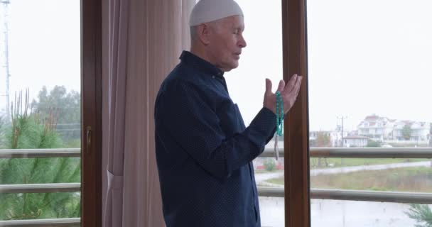 Een oude man met rozenkransen biddend — Stockvideo