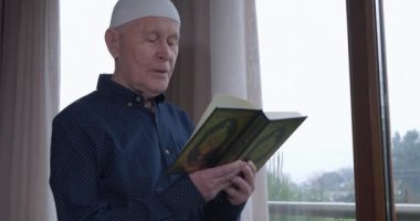 Evde Kuran okuyan yaşlı bir müslüman.