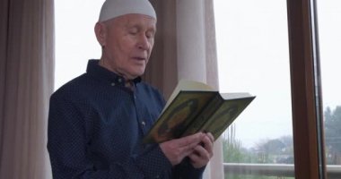 Evde Kuran okuyan yaşlı bir müslüman.