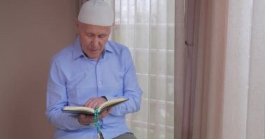 Evde Kuran okuyan yaşlı bir müslüman.