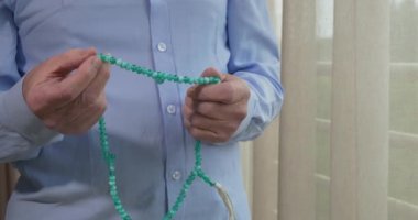 Tespih taşıyan yaşlı bir adamın dua eden elleri.