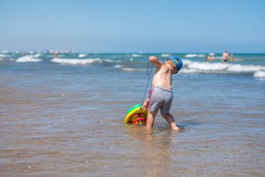 Küçük çocuk kumsalda oynuyor.