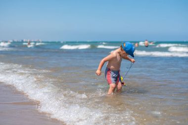 Küçük çocuk kumsalda oynuyor.