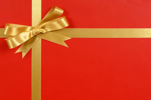 Altın yay hediye şerit kırmızı arka plan — Stok fotoğraf