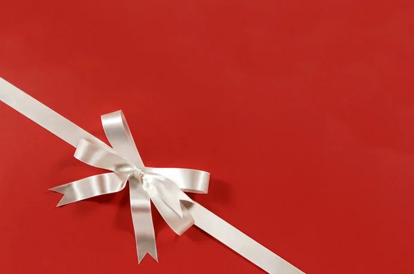 Vit gåva båge band rött papper bakgrund hörnet diagonalt — Stockfoto
