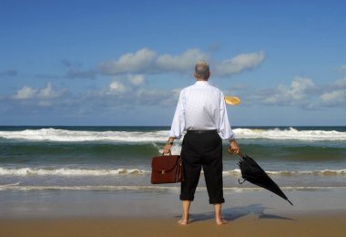 Businessman gazing out to sea lost in thought clipart