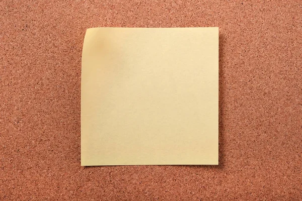 Yellow sticky post note on cork board — Stock Photo, Image