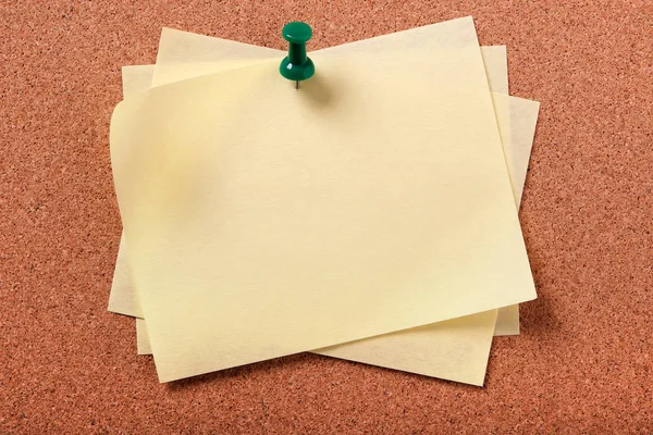 Several untidy yellow sticky post notes pinned to cork board — Stock Photo, Image
