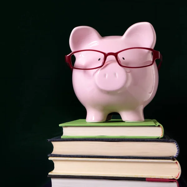 Piggy banco óculos livros quadro negro — Fotografia de Stock