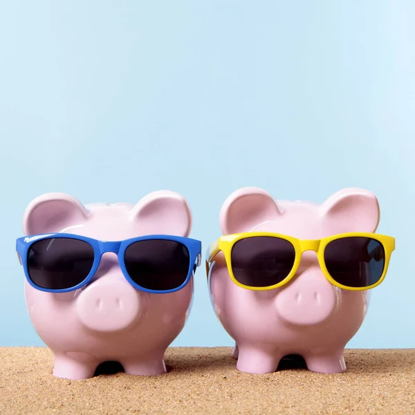 Two piggy banks beach sunglasses travel money saving — Stock Photo, Image