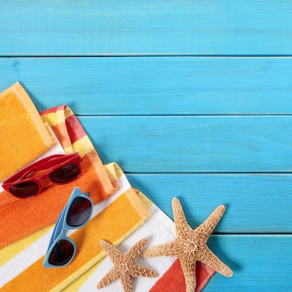 与橙色条纹的毛巾 海星和太阳镜上旧的蓝色的海滩场面描绘的木地板 副本的空间 — 图库照片