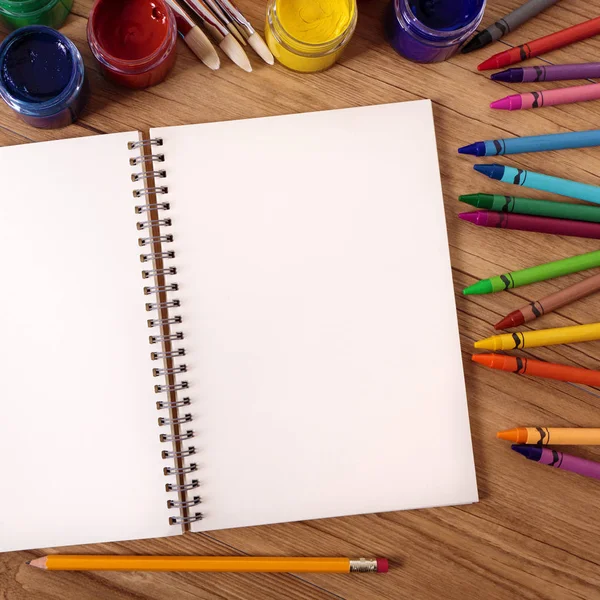 Caderno aberto branco em branco em uma mesa da escola com várias tintas , — Fotografia de Stock