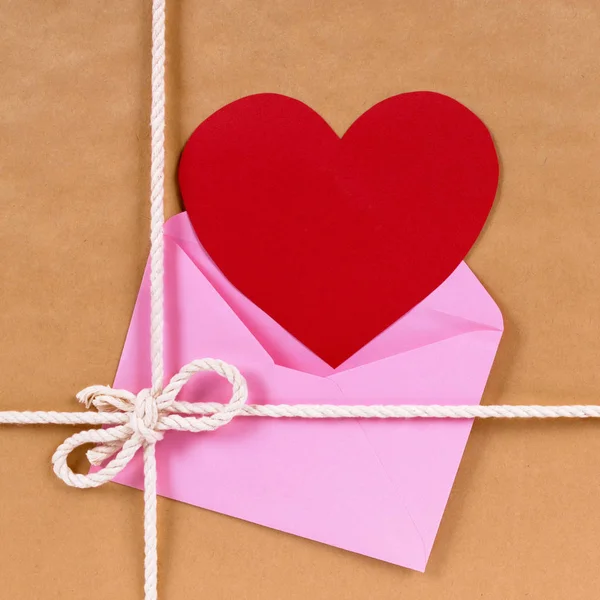 Regalo de San Valentín con tarjeta de corazón rojo o etiqueta de regalo, paquete de papel marrón —  Fotos de Stock