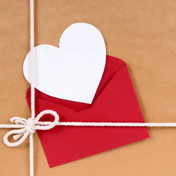 Regalo de San Valentín con tarjeta de forma de corazón blanco, sobre rojo, b Imagen de archivo