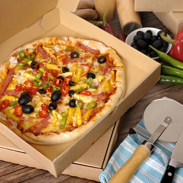 Frisch gebackene Pizza im Lieferkarton mit Zutaten. — Stockfoto