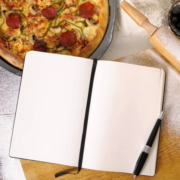 Pizza with notebook and ingredients — Stock Photo, Image