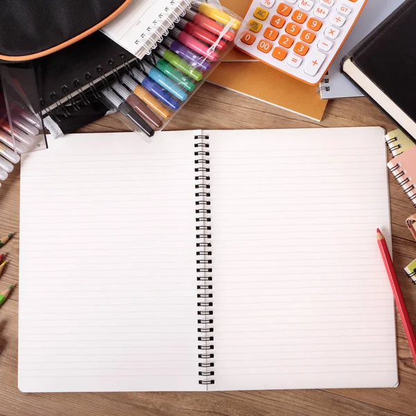 Busy student's desk with blank open notebook — Stock Photo, Image