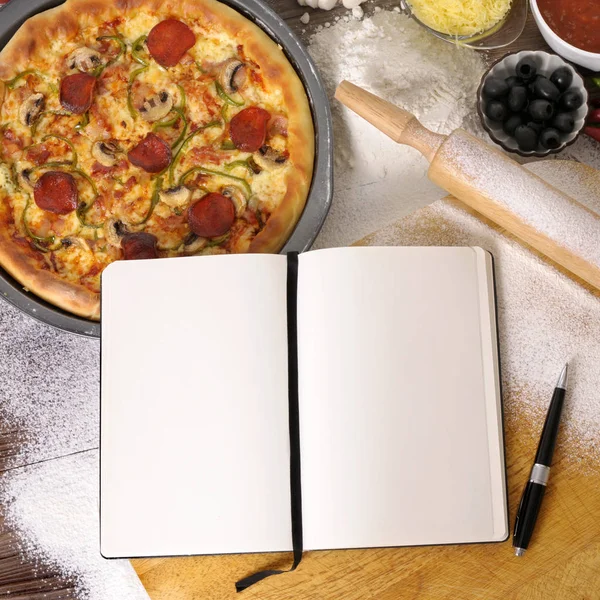 Pizza con cuaderno e ingredientes Imágenes de stock libres de derechos
