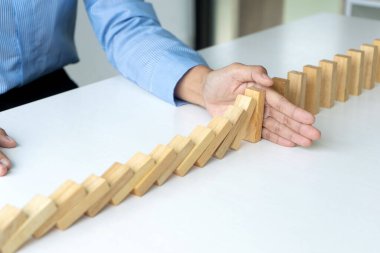 Genç iş adamları, ahşap blogu durdurmak için eli kullanıyor.