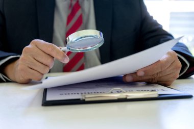 Lawyer or judge use magnifier glass look to the paper for inspection examination to the law case clipart