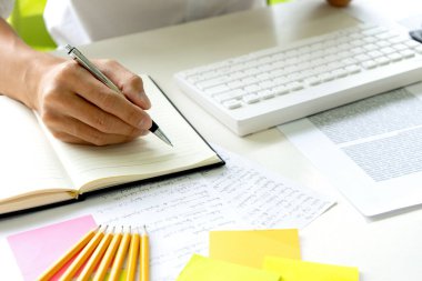 Kadın ve erkek eğitim veya iş için dizüstü bilgisayar ve kağıt işi renk kalemleriyle masada çalışırlar.