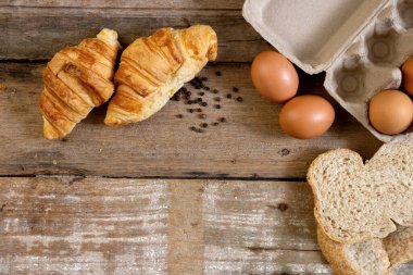 Taze pişmiş Fransız kruvasan fırını ve meşe ağacından yapılmış masa üzerinde yumurta.