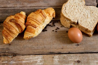 Taze pişmiş Fransız kruvasan fırını ve meşe ağacından yapılmış masa üzerinde yumurta.