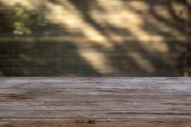 Boş ahşap masa, bulanık arka plan ışığı ve kahverengi tonda gölge.