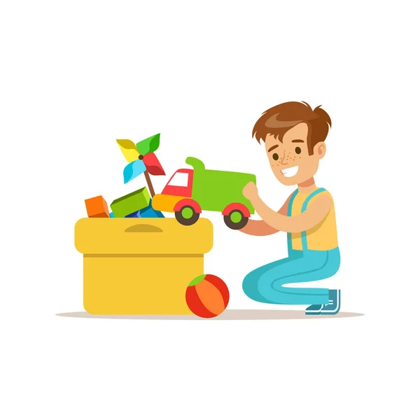 Menino colocando seus brinquedos em caixa especial sorrindo personagem de criança dos desenhos animados ajudando com limpeza de casa e limpeza de casa — Vetor de Stock
