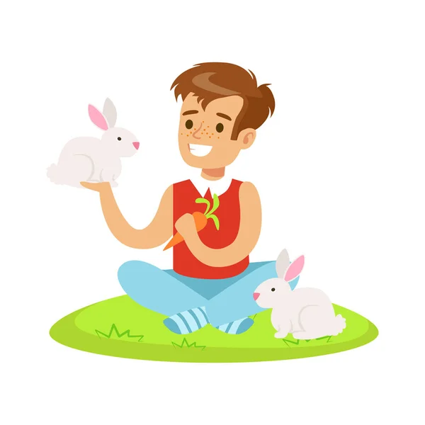 Smiling boy sitting on green grass, playing and feeding two white rabbits with carrot. Colorful cartoon character vector Illustration — Stock Vector