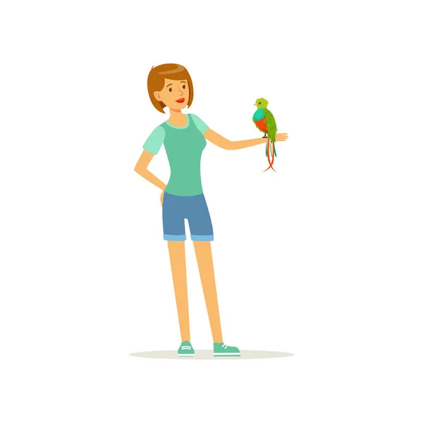 Mujer sosteniendo un pájaro tropical con plumas de colores en la mano. Personaje femenino sonriente y loro guacamayo. Mascotas y amistad. Animal doméstico. Diseño de vector plano — Vector de stock