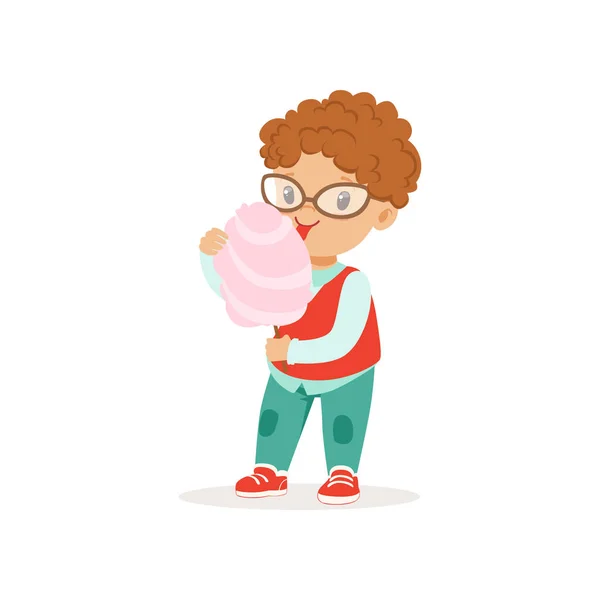 Lustiger kleiner Junge mit glänzenden Augen, der süße Zuckerwatte isst. Zeichentrickfigur mit lockigem rotem Haar, Brille, Hemd, Weste und Jeans. flache Vektorkonstruktion — Stockvektor