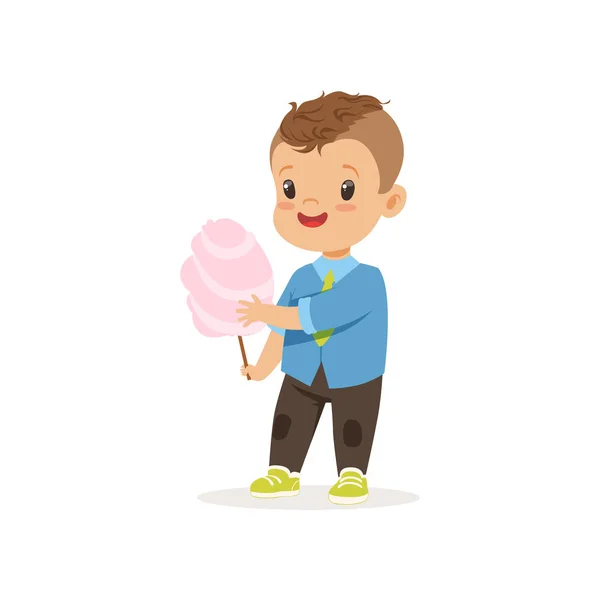 Стильный дошкольник, стоящий со сладкой сахарной ватой. Мультфильм маленький мальчик персонаж с каштановыми волосами в голубой рубашке и коричневых брюках. Плоский векторный дизайн — стоковый вектор