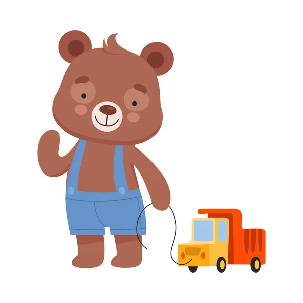ロープベクトルイラストでおもちゃトラックを引っ張るプレイスーツを身に着けている笑顔クマキャラクター — ストックベクタ
