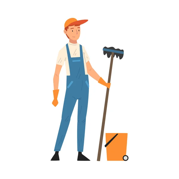 Profesjonalny sprzątacz stojący z mopem i wiadrem, męski charakter pracownika ubrany w niebieskie ogrodniczki i rękawiczki gumowe, personel firmy sprzątającej Wektor ilustracji — Wektor stockowy