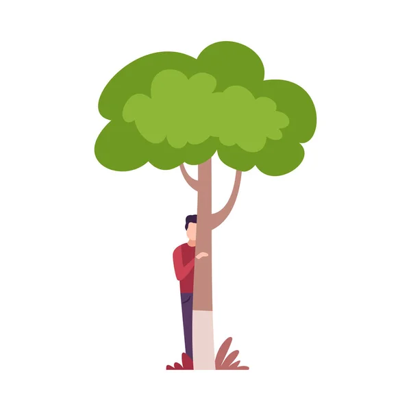 緑の木の後ろに隠れて見る若い男｜ベクトルイラスト — ストックベクタ